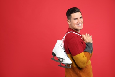 Happy man with ice skates on red background. Space for text