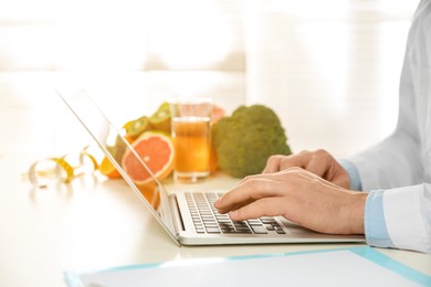 Image of Nutritionist working with laptop at desk in office, closeup