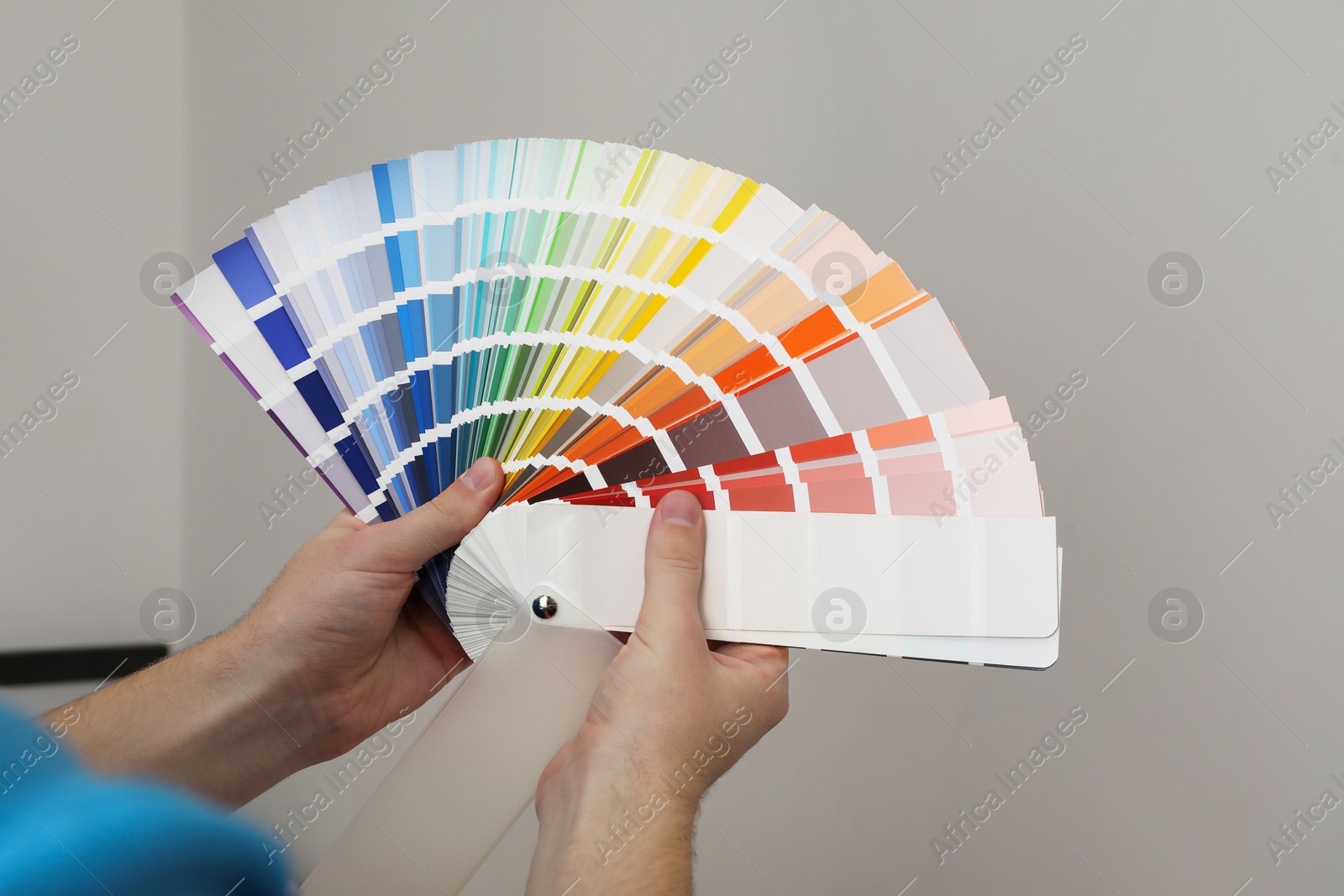 Photo of Man with palette choosing color for painting wall indoors, closeup. Interior design