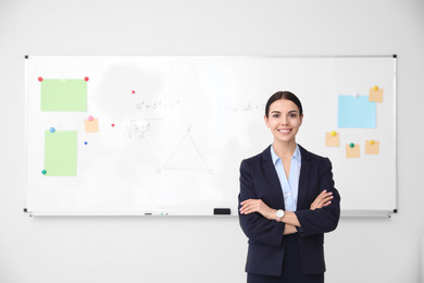 Photo of Young teacher near whiteboard in modern classroom. Space for text