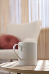 Photo of White mug on wooden table indoors, space for text
