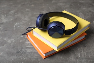 Photo of Modern headphones with hardcover books on grey background