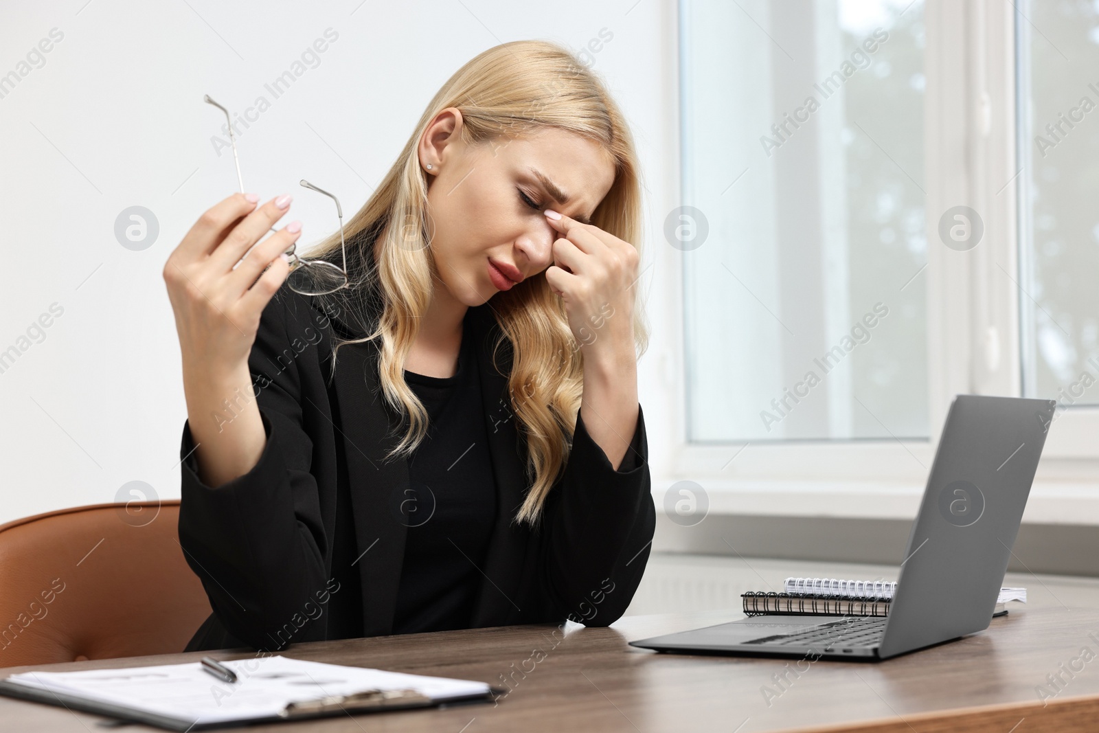 Photo of Overwhelmed woman with glasses at wooden table in office