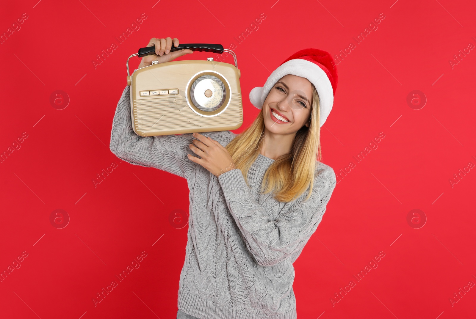 Photo of Happy woman with vintage radio on red background. Christmas music