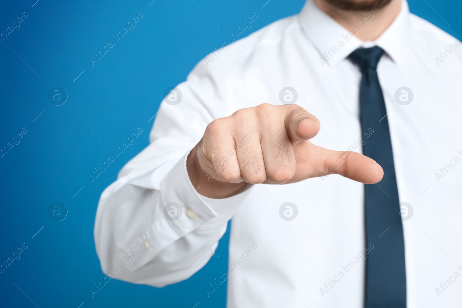 Photo of Businessman touching something against light blue background, focus on hand