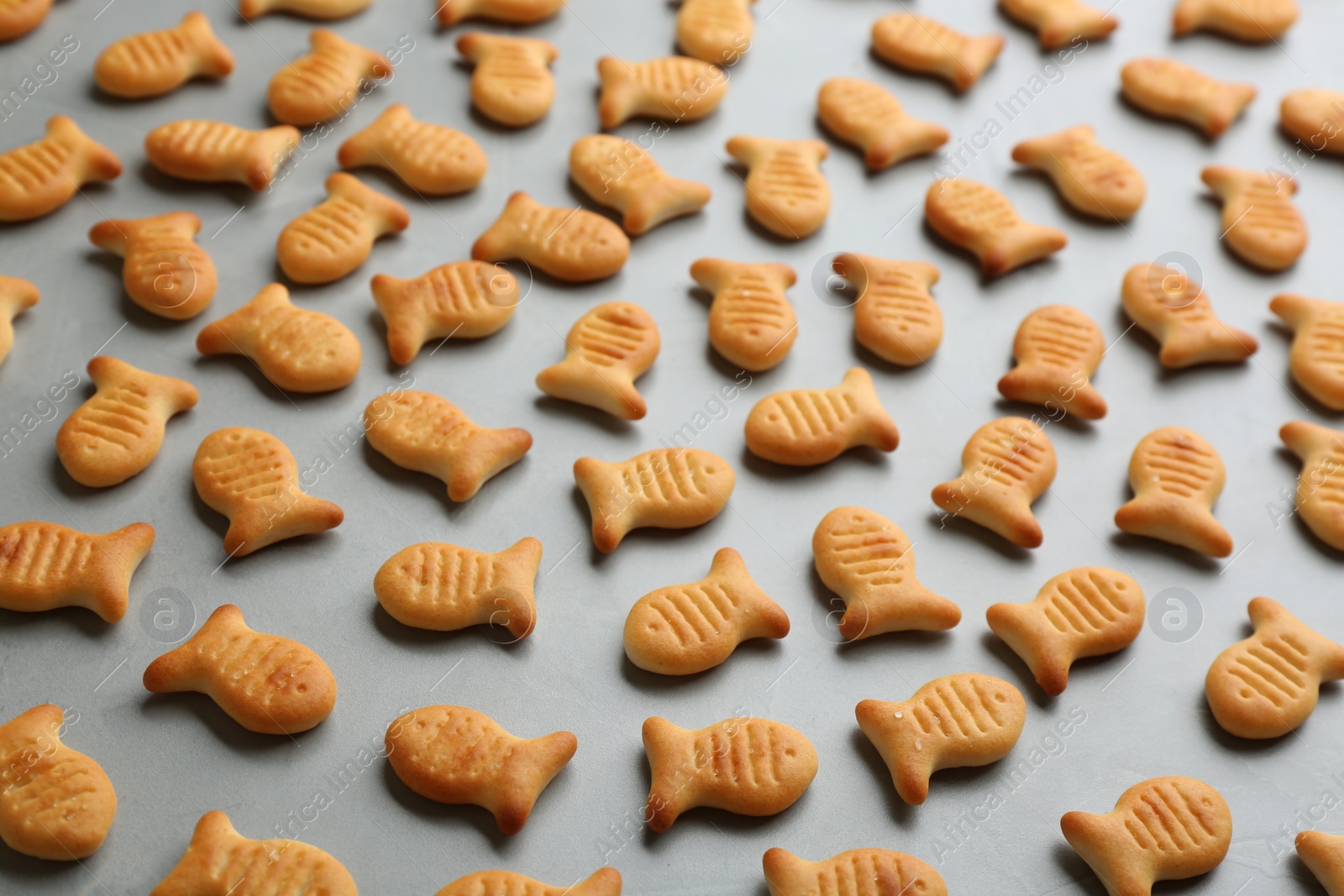 Photo of Delicious goldfish crackers on grey table, closeup