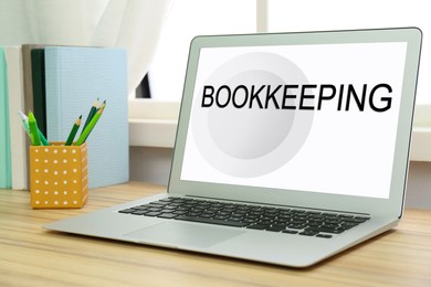 Image of Bookkeeping concept. Modern laptop and stationery on wooden table