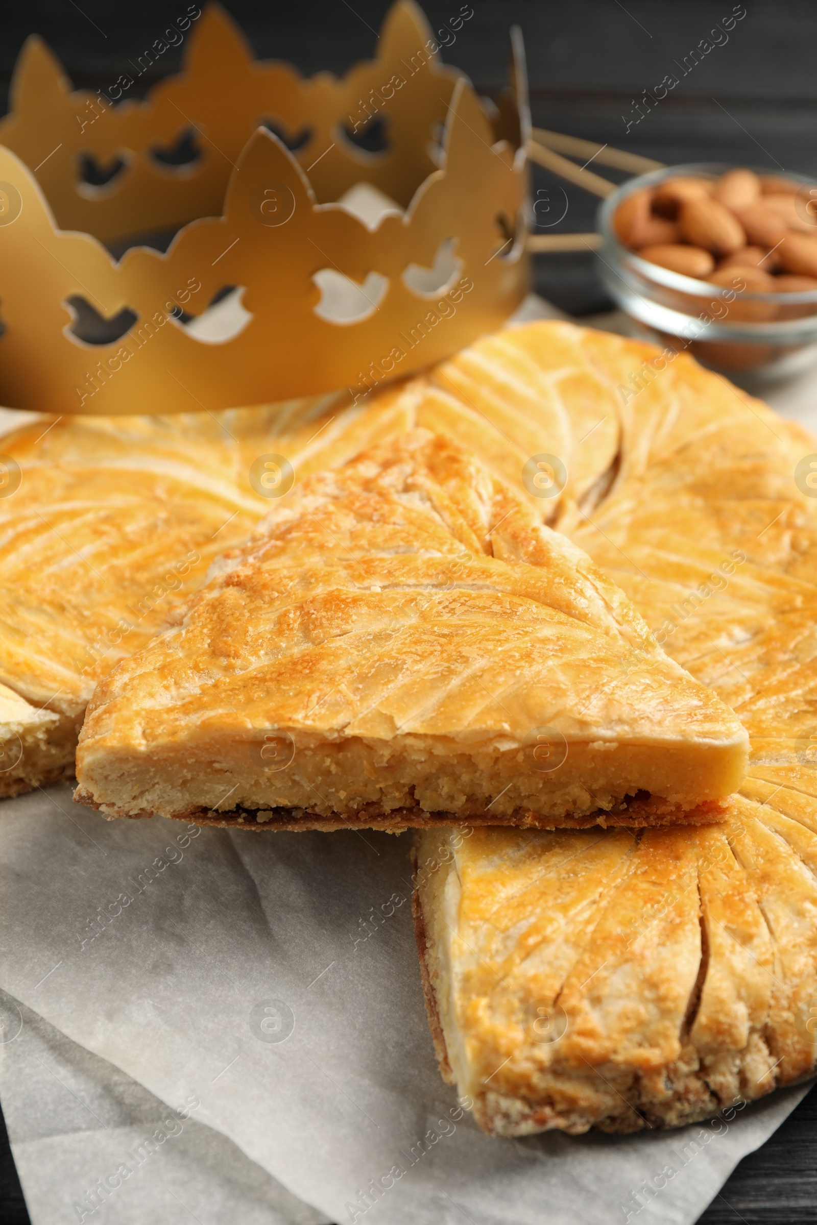 Photo of Traditional galette des Rois with paper crown on table, closeup