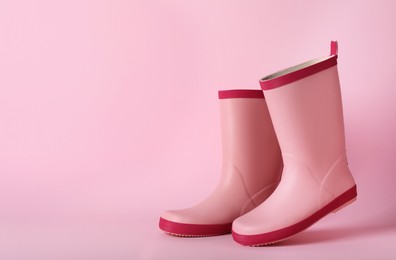 Photo of Pair of rubber boots on pink background, space for text