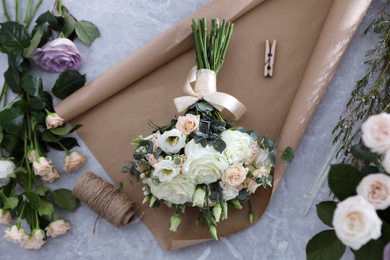 Beautiful wedding bouquet and paper sheet on light grey marble table, top view