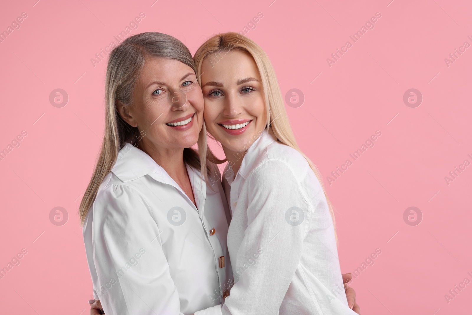 Photo of Family portrait of young woman and her mother on pink background