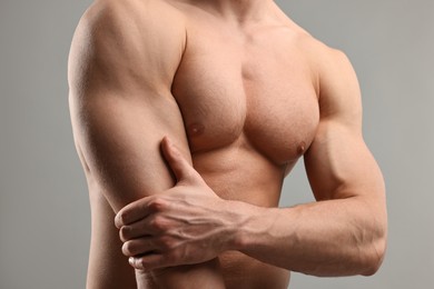 Man with muscular body on light grey background, closeup