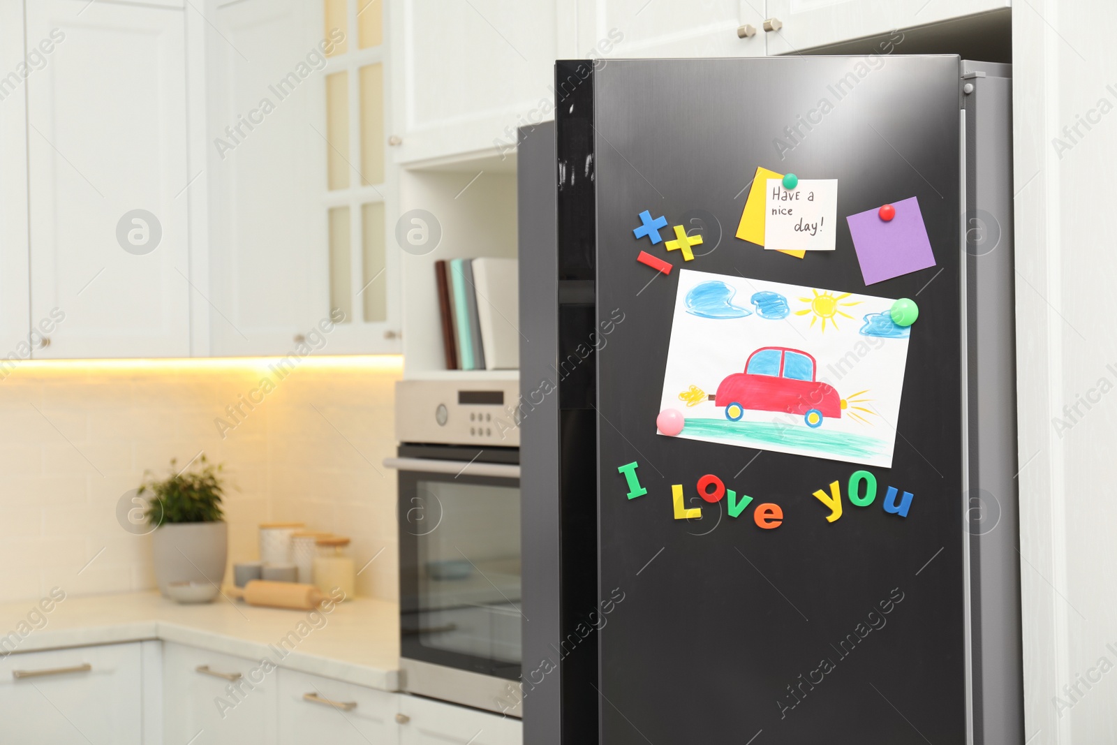Photo of Modern refrigerator with child's drawing, notes and magnets in kitchen. Space for text