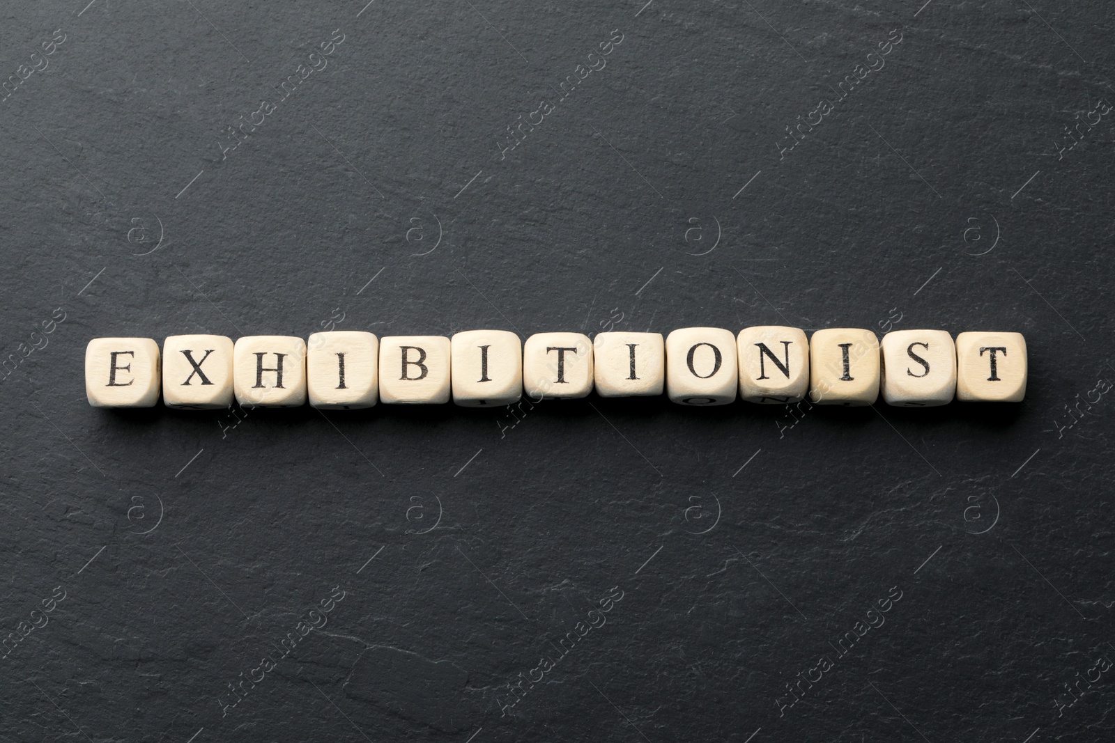 Photo of Word EXHIBITIONIST made with wooden cubes on black table, flat lay