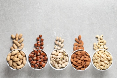 Photo of Flat lay composition with organic nuts and space for text on grey background, top view. Snack mix