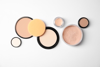 Flat lay composition with different makeup face powders on white background