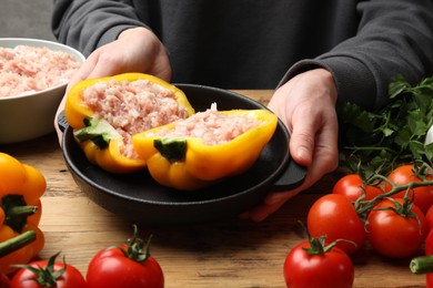 Photo of Woman making stuffed peppers with ground meat at wooden table, closeup