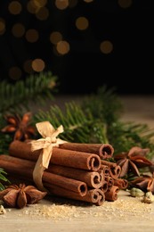 Different aromatic spices and fir branches on wooden table, space for text