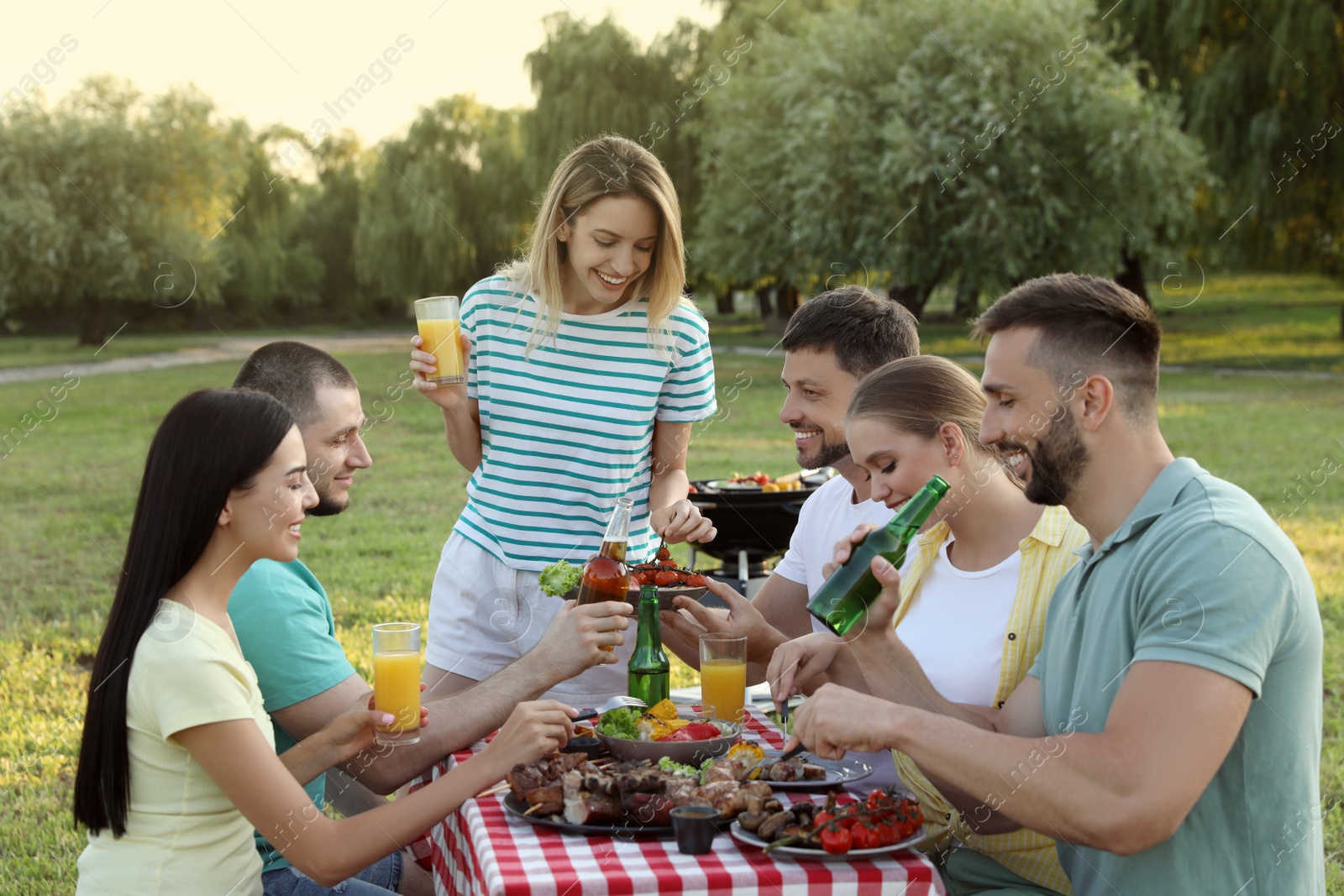 Photo of Happy friends with drinks and food at barbecue party in park