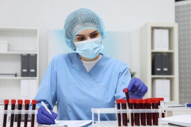 Laboratory testing. Doctor with blood samples in tubes at white table indoors