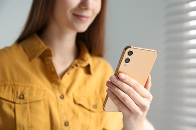 Photo of Young woman using modern smartphone indoors, closeup