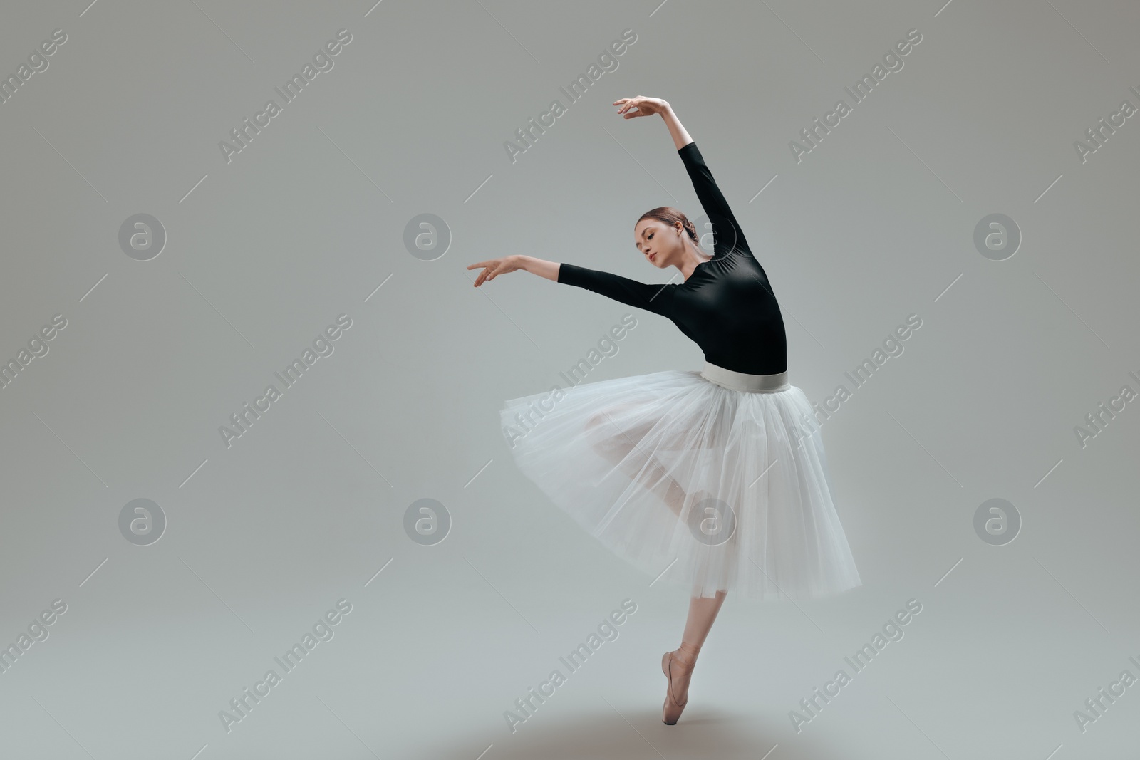 Photo of Young ballerina practicing dance moves on light grey background. Space for text