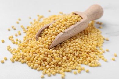 Photo of Scoop with millet groats on white table, closeup