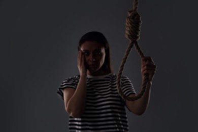 Photo of Depressed woman with rope noose on grey background