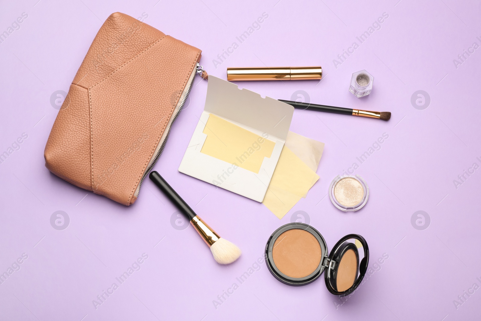 Photo of Facial oil blotting tissues and different decorative cosmetics on violet background, flat lay. Mattifying wipes
