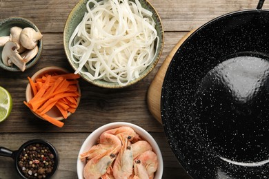 Photo of Flat lay composition with black wok, spices and products on wooden table