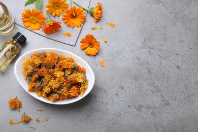 Photo of Dry and fresh calendula flowers with tincture on light grey table, flat lay. Space for text