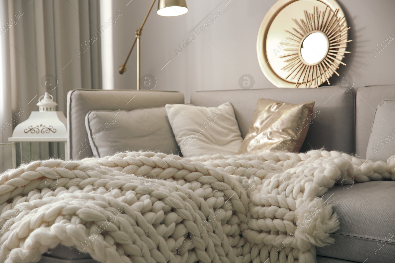 Photo of Warm knitted blanket on grey sofa in living room. Interior design