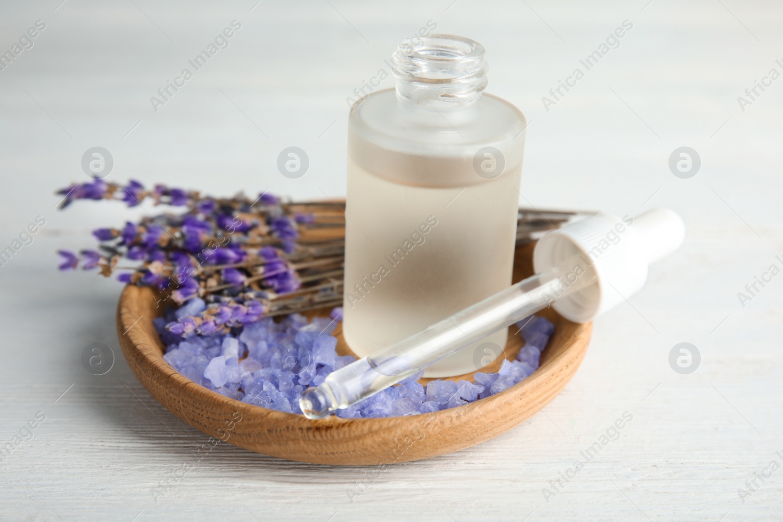 Photo of Bottle with aromatic lavender oil on white wooden table