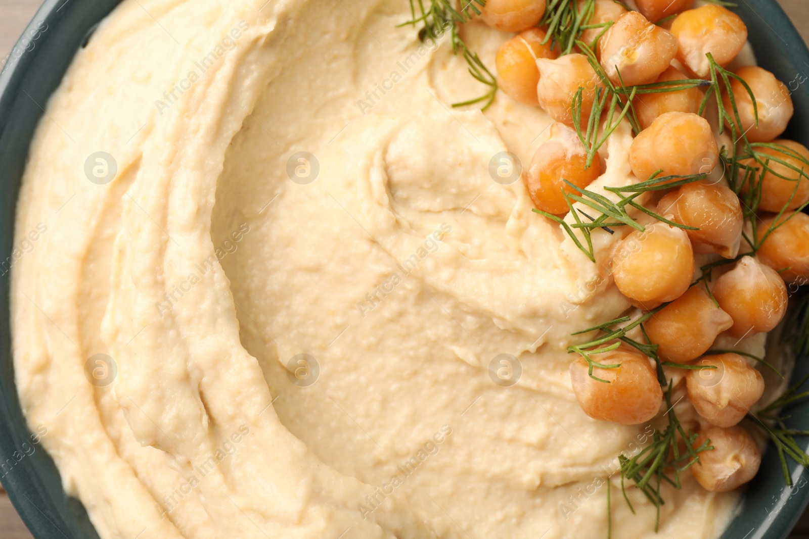 Photo of Bowl of tasty hummus with chickpeas and dill as background, top view