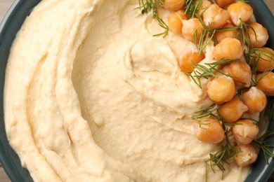 Bowl of tasty hummus with chickpeas and dill as background, top view