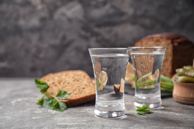 Photo of Cold Russian vodka with snacks on grey table, closeup