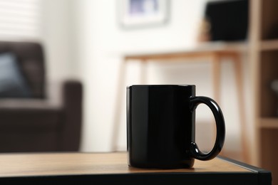 Photo of Black mug on wooden table indoors. Mockup for design