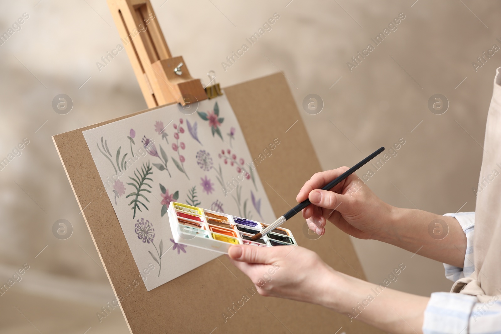 Photo of Woman painting flowers with watercolors in workshop, closeup