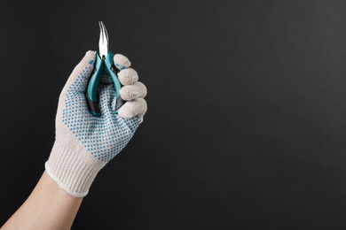 Photo of Man with bent nose pliers on black background, closeup. Space for text