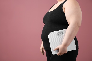 Overweight woman with scales on color background