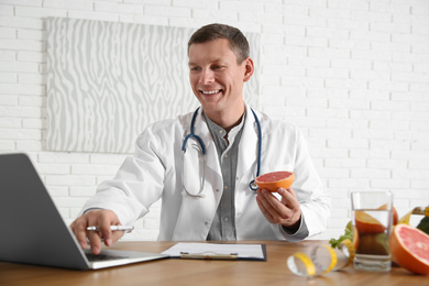 Photo of Nutritionist working with laptop at desk in office