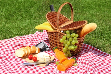 Photo of Basket with food on blanket prepared for picnic in park