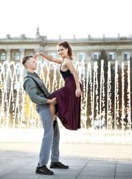 Beautiful young couple practicing dance moves near fountain outdoors