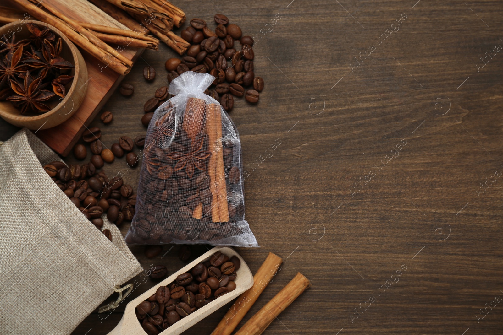 Photo of Scented sachet with coffee beans, anise and cinnamon on wooden table, flat lay. Space for text