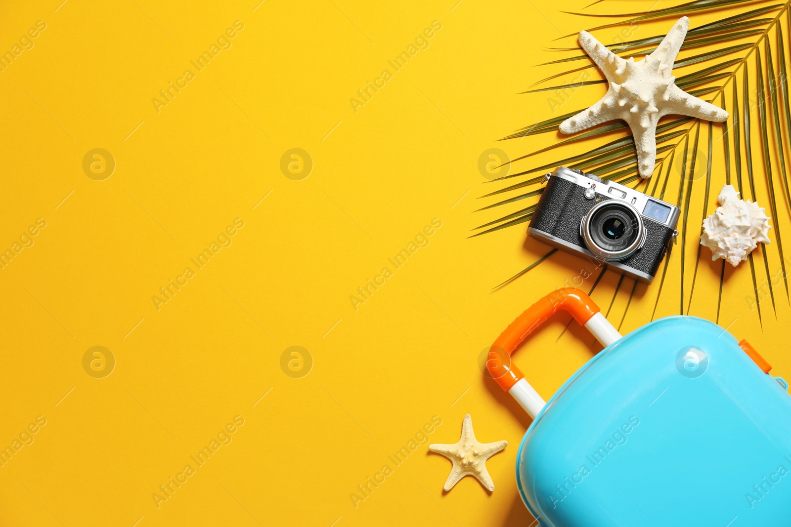 Photo of Flat lay composition with small suitcase and camera on color background, space for text. Beach accessories