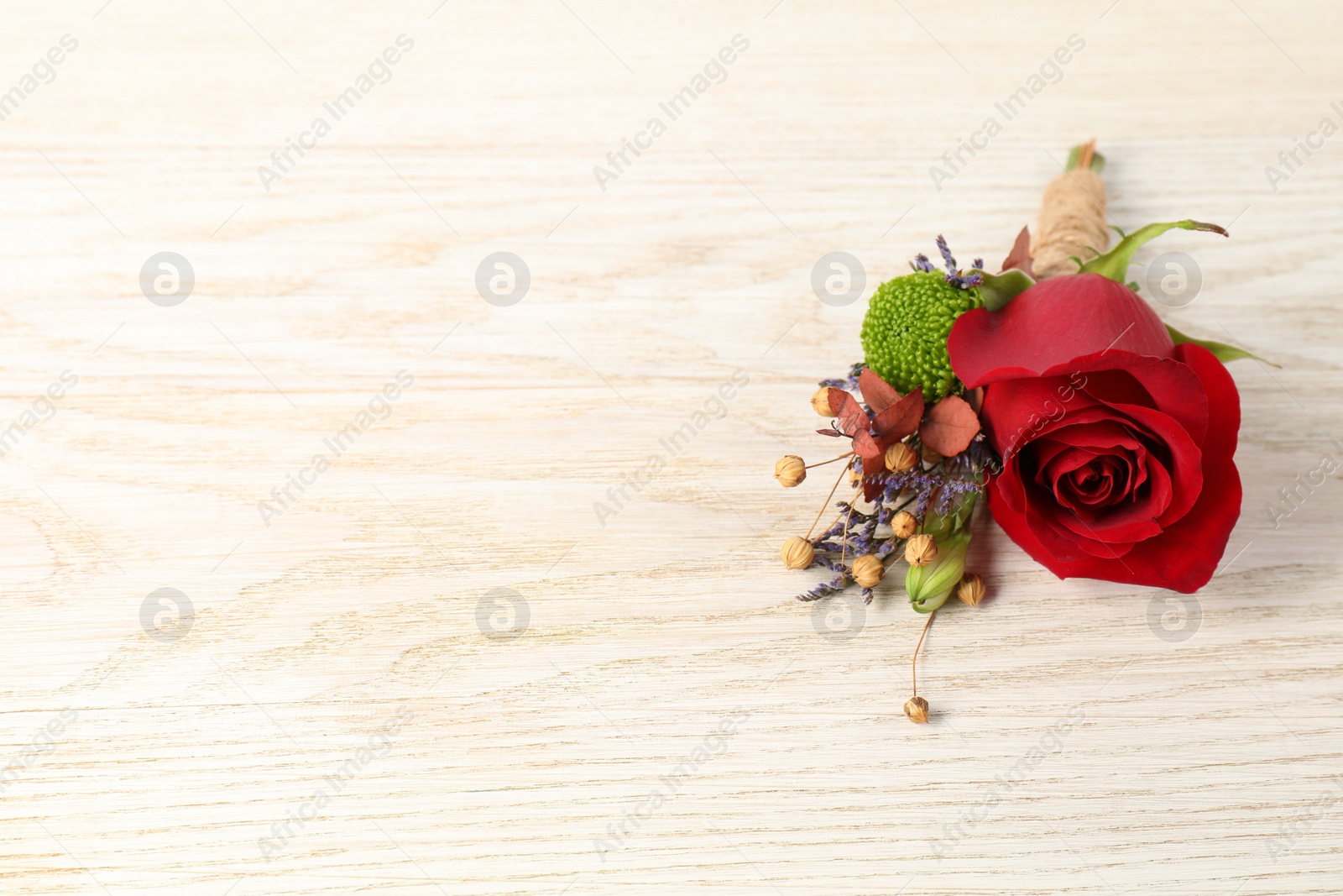 Photo of Stylish boutonniere with red rose on light wooden table. Space for text