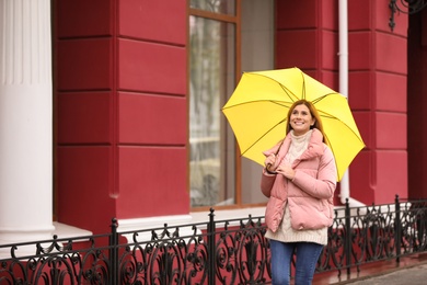 Woman with umbrella in city on autumn rainy day