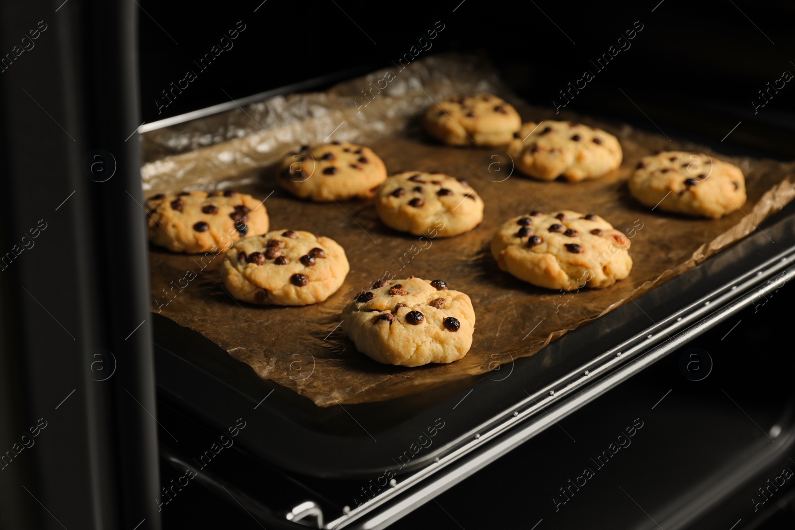 Photo of Baking delicious chocolate chip cookies in oven, closeup