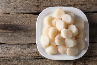 Photo of Fresh raw scallops on wooden table, top view. Space for text