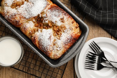 Photo of Delicious yeast dough cake in baking pan and milk on wooden table, flat lay